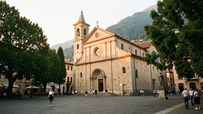 Église paroissiale historique de Côme éclairée par la lumière dorée du soir, entourée d’une place paisible et d’arbres.