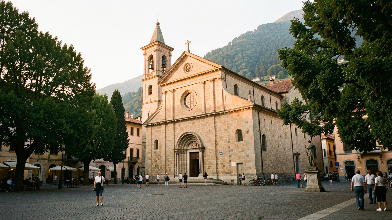 Église paroissiale historique de Côme éclairée par la lumière dorée du soir, entourée d’une place paisible et d’arbres.